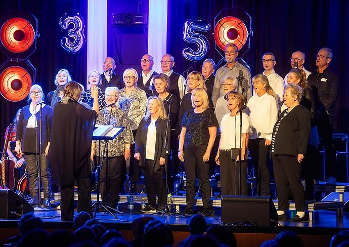 En kör som står på en scen och sjunger