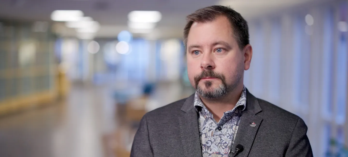 En man i kostym och slips står i en korridor.