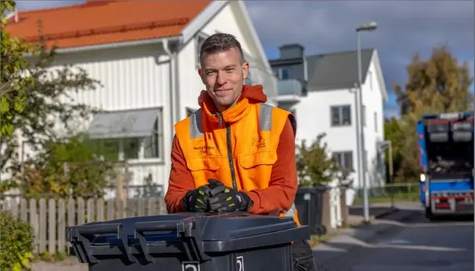 Bilden visar en medarbetare som tittar in i kameran och vilar överkroppen mot ett sopkärl.