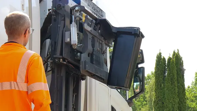 En sopbil med en speciell arm på sidan som kan hämta upp en soptunna.